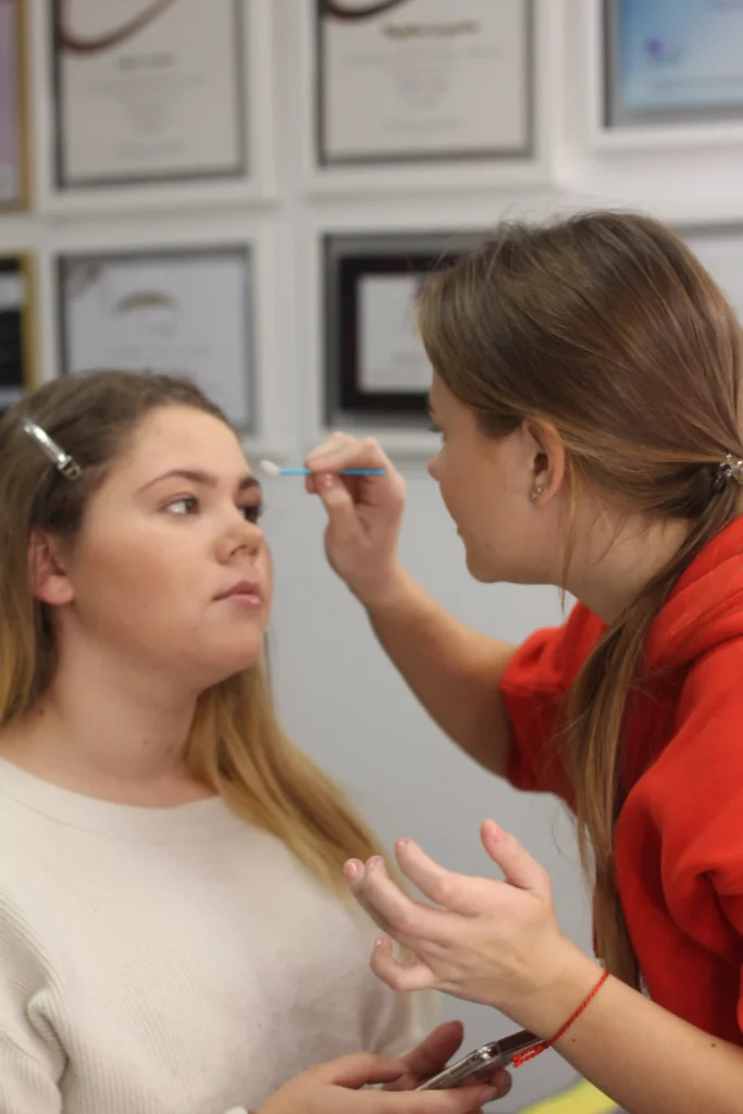 Elina mapping a client's brow shape with a pencil before treatment