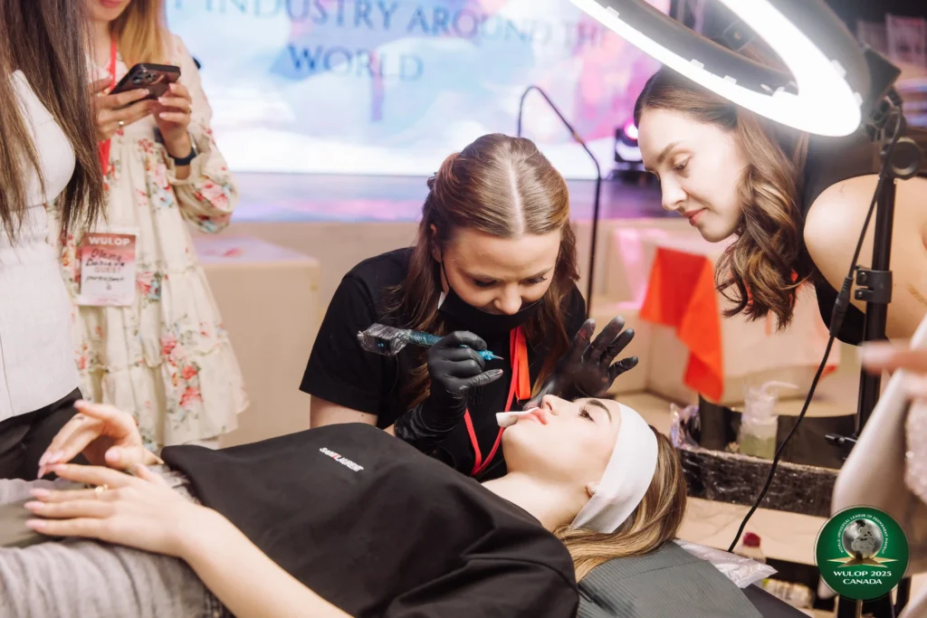 Elina demonstrating a permanent makeup technique while another artist observes